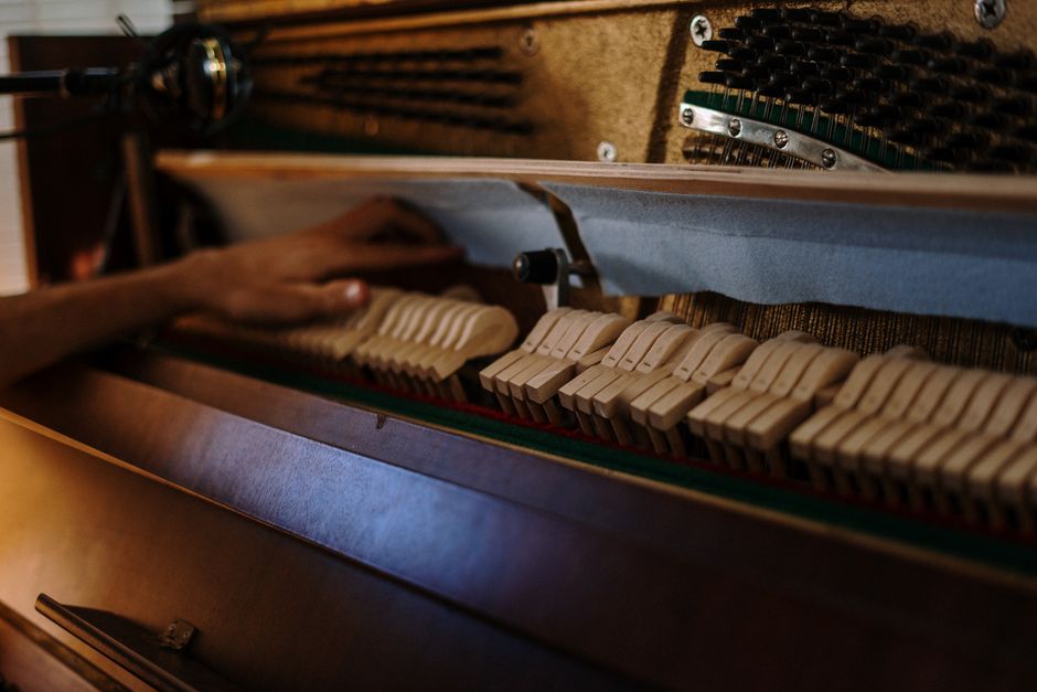 Technician regulating complex piano key action mechanics in workshop